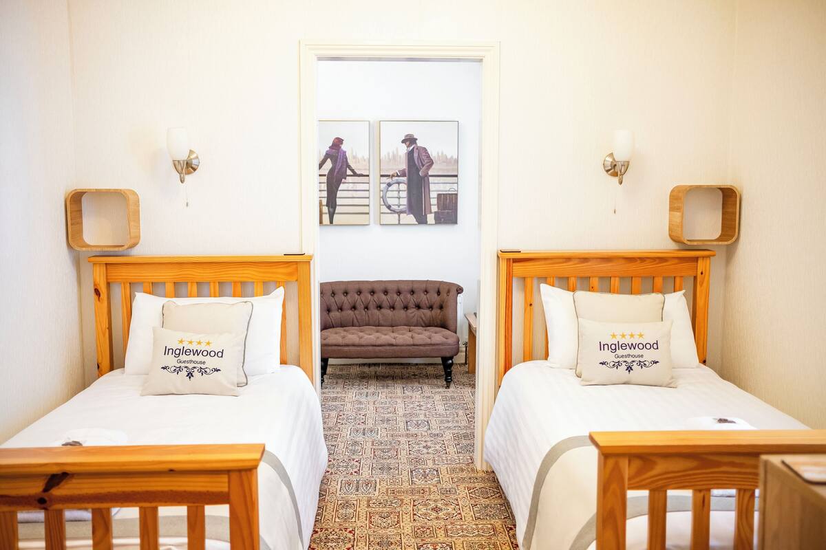 A hotel room with two wooden beds, a patterned carpet, and a sofa.