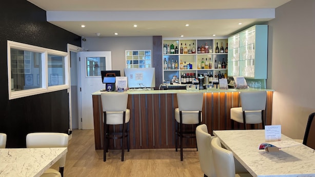 A bar area with a counter, seating, and a display of liquor bottles. - Opul Express (Douglas)