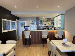 A bar area with a counter, seating, and a display of liquor bottles. - Opul Express (Douglas)