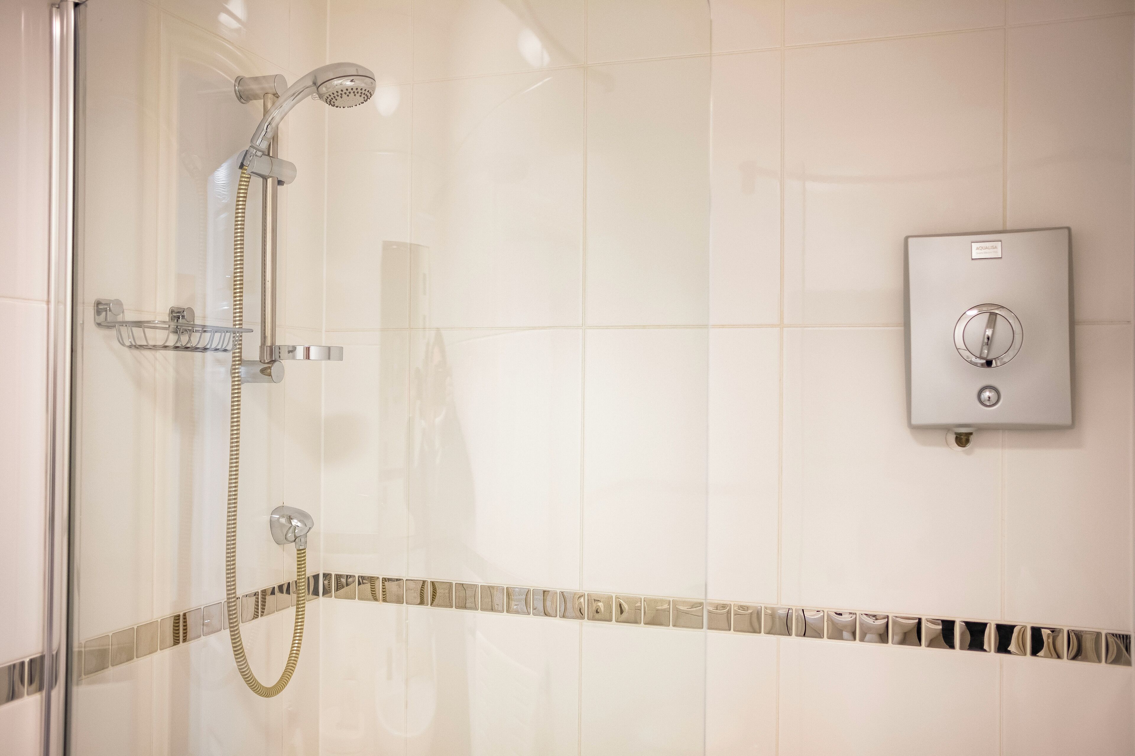 Ducha con cabezal de ducha de mano y panel de control en la pared.