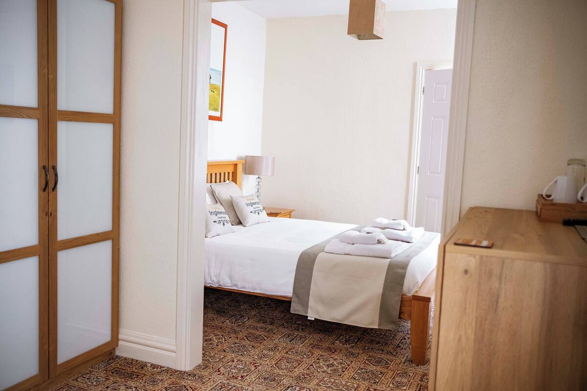 A bedroom with a bed, bedside table, and a wardrobe.