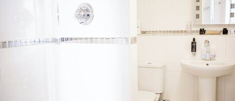 A bathroom with a shower, toilet, and sink.