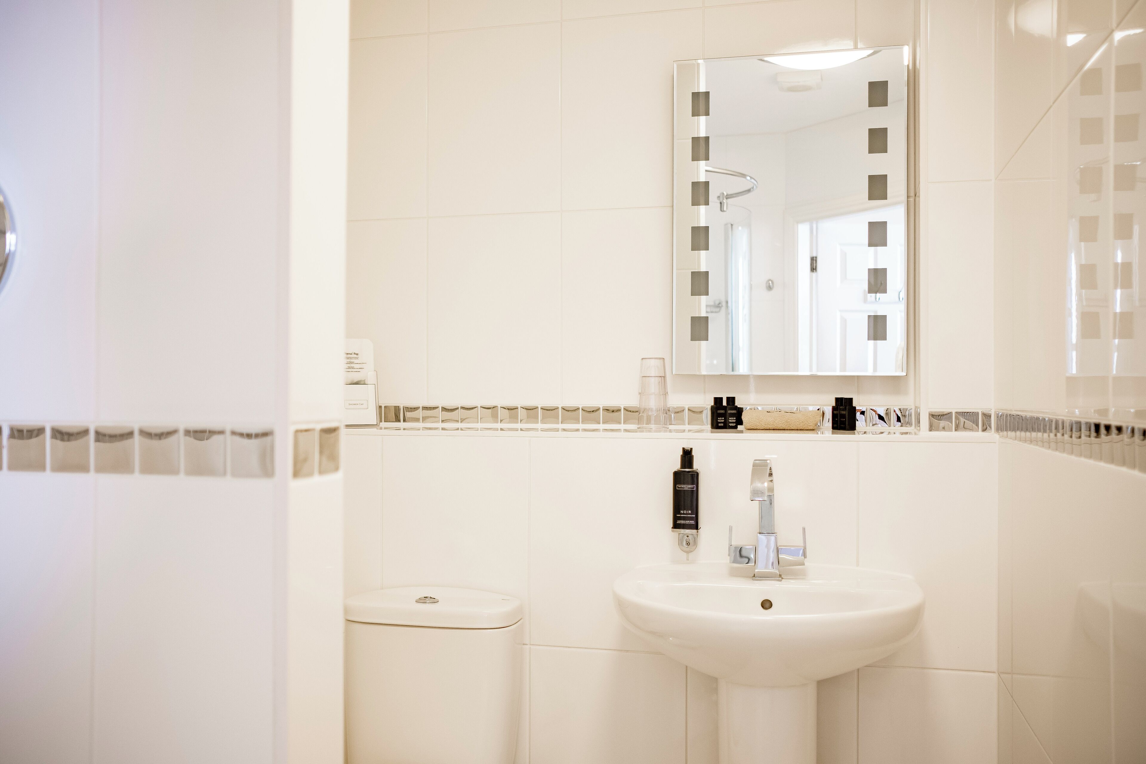A bathroom with a white sink, a mirror, and a toilet.