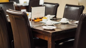 A dining table set for six with dark brown chairs, white plates, and silverware. - Opul Express (Douglas)