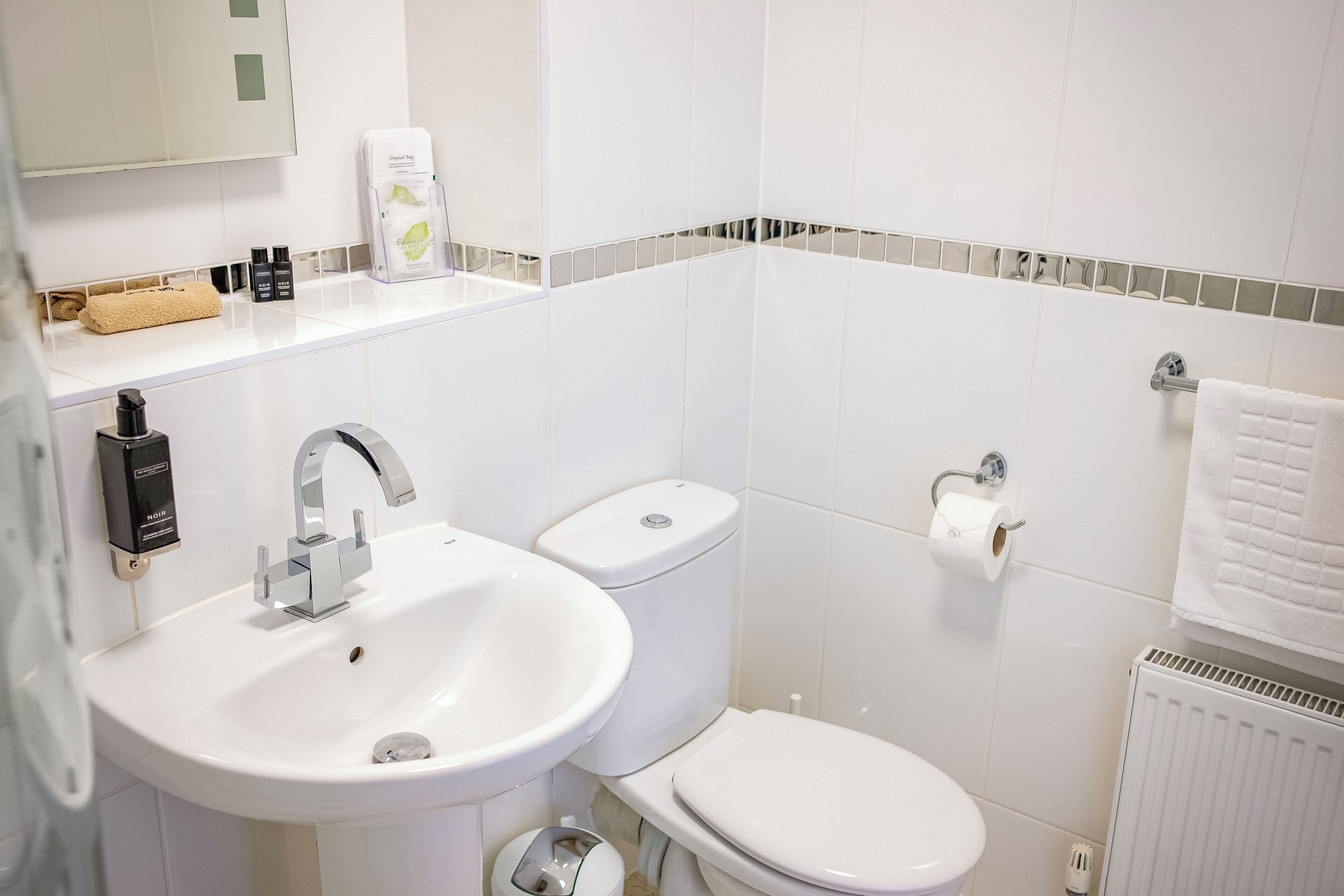 Une salle de bain avec un lavabo blanc, des toilettes et un porte-serviettes.
