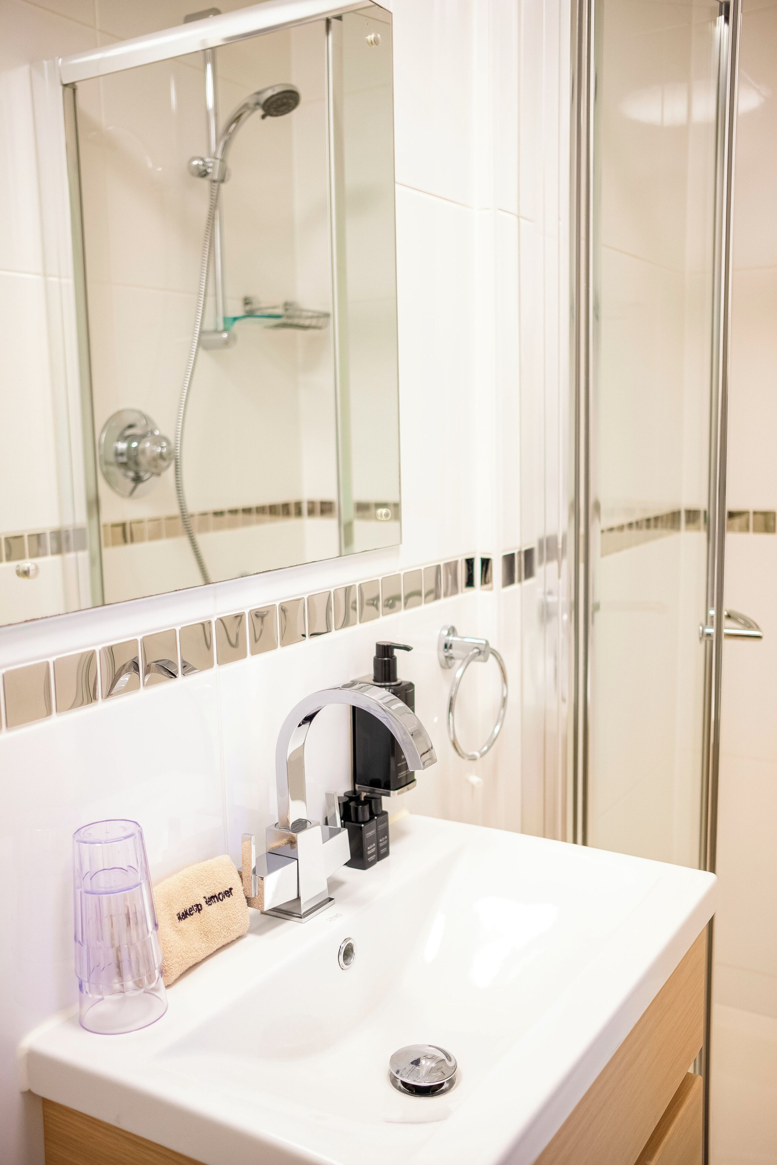 A bathroom with a white sink, a glass shower enclosure, and a mirror above the sink.