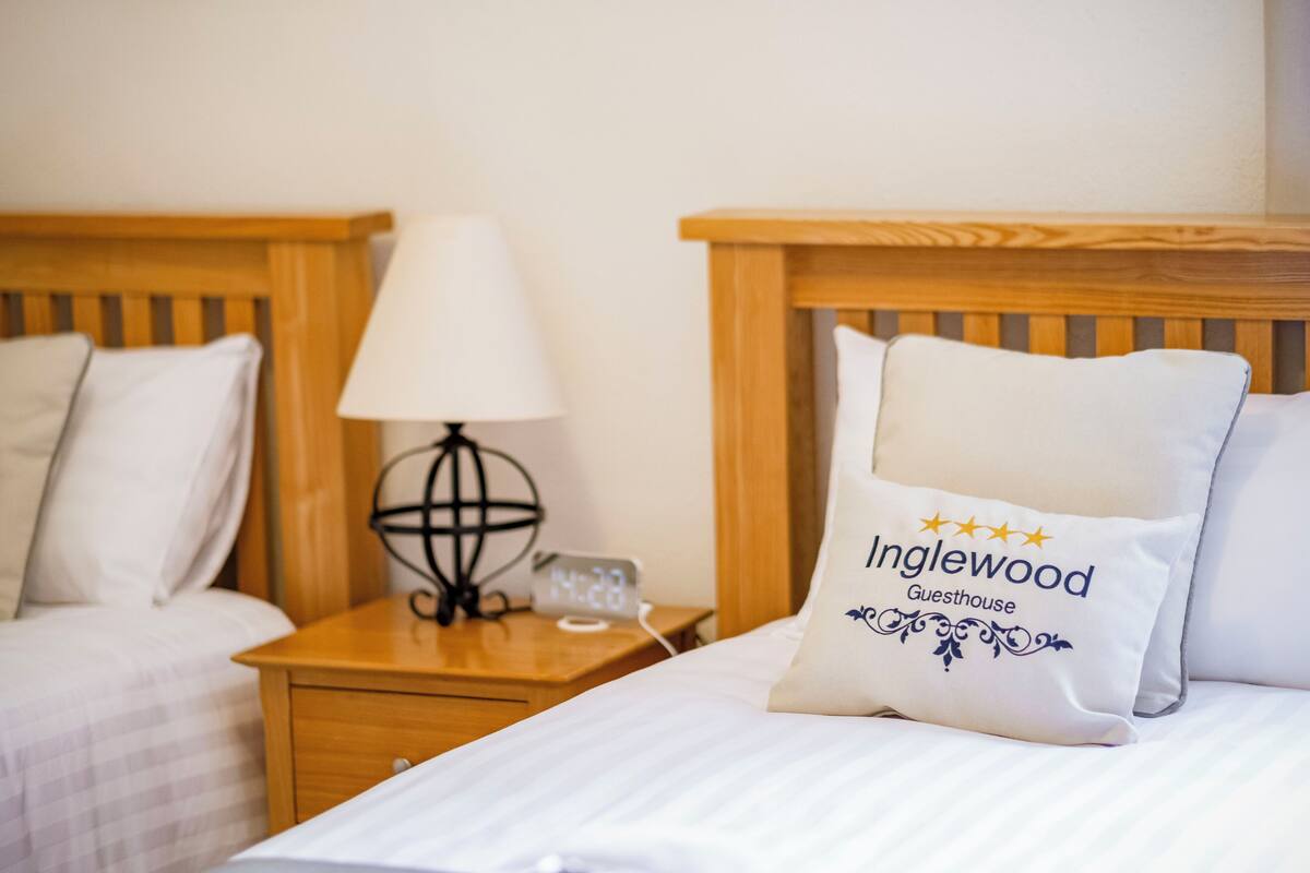 A hotel room with two beds, a nightstand with a lamp, and a decorative globe.