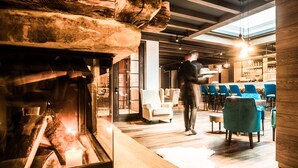 A modern interior with a fireplace, wooden beams, and a bar area with blue chairs.