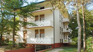A multi-story building with balconies, surrounded by trees. - Lignano Pineta near Beach (Lignano Sabbiadoro)