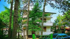 A multi-story residential building with a white facade and balconies. - Lignano Pineta near Beach (Lignano Sabbiadoro)