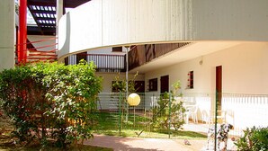 Um pátio com área cercada, um caminho e um edifício com varanda.
