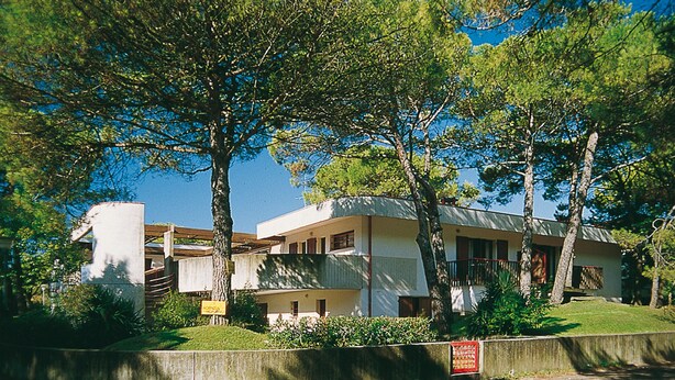 Um edifício de dois andares com telhado plano e varanda no segundo andar.