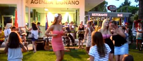 A group of people gathered outside a building with a sign reading "AGENZIA LIGNANO".