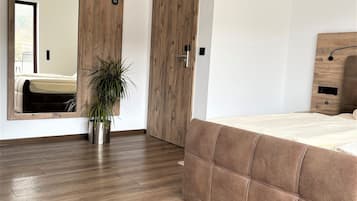 Ein modernes Schlafzimmer mit einem großen Spiegel, einem Holzschrank und einem Bett mit Kopfteil.