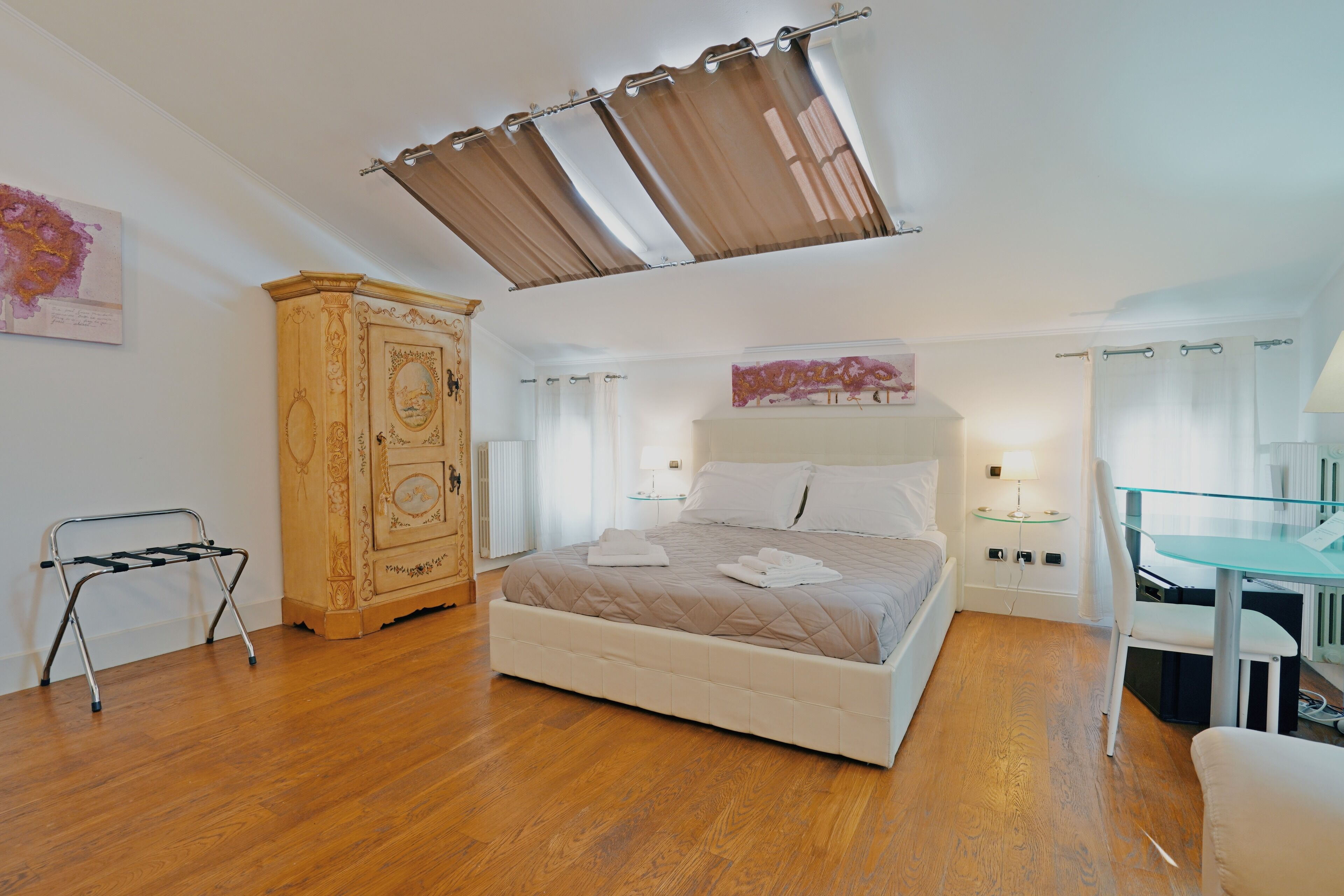 Un dormitorio con cama, armario de madera, mesita de cristal y una silla.