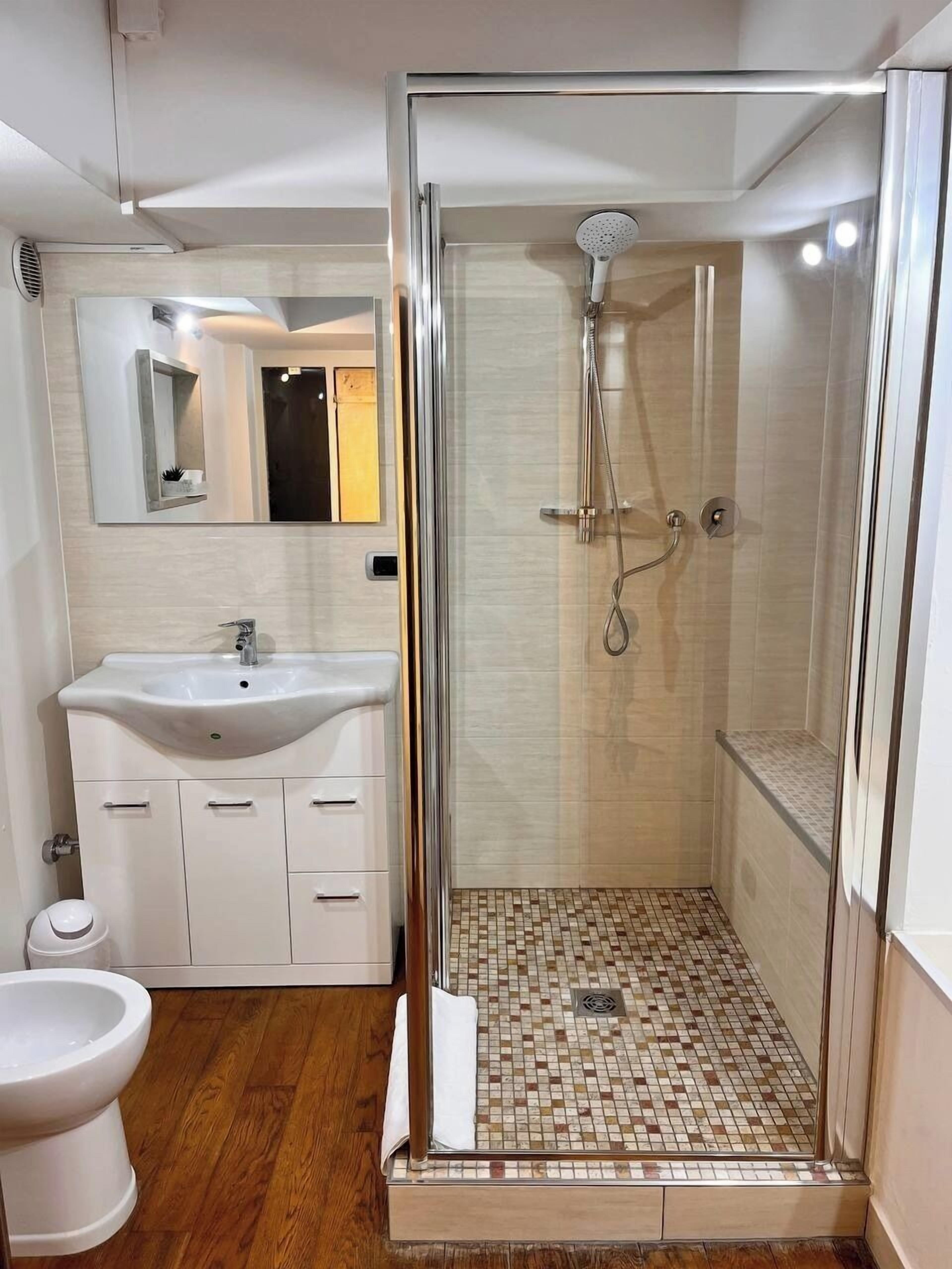 A bathroom with a glass-enclosed shower, a white sink, and a toilet.