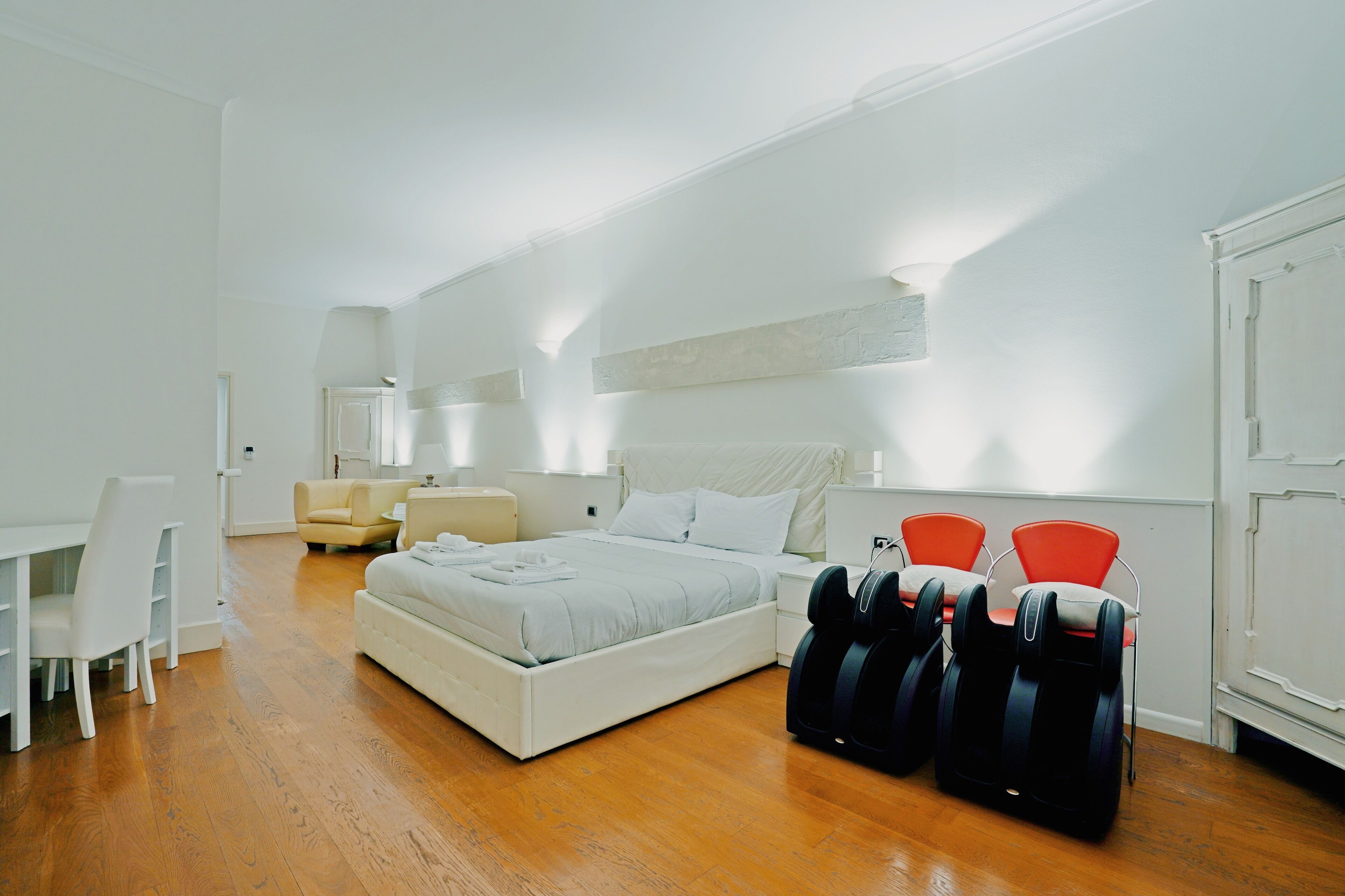 Une chambre d’hôtel moderne équipée d’un grand lit, d’un bureau, d’une chaise et d’un fauteuil de massage.