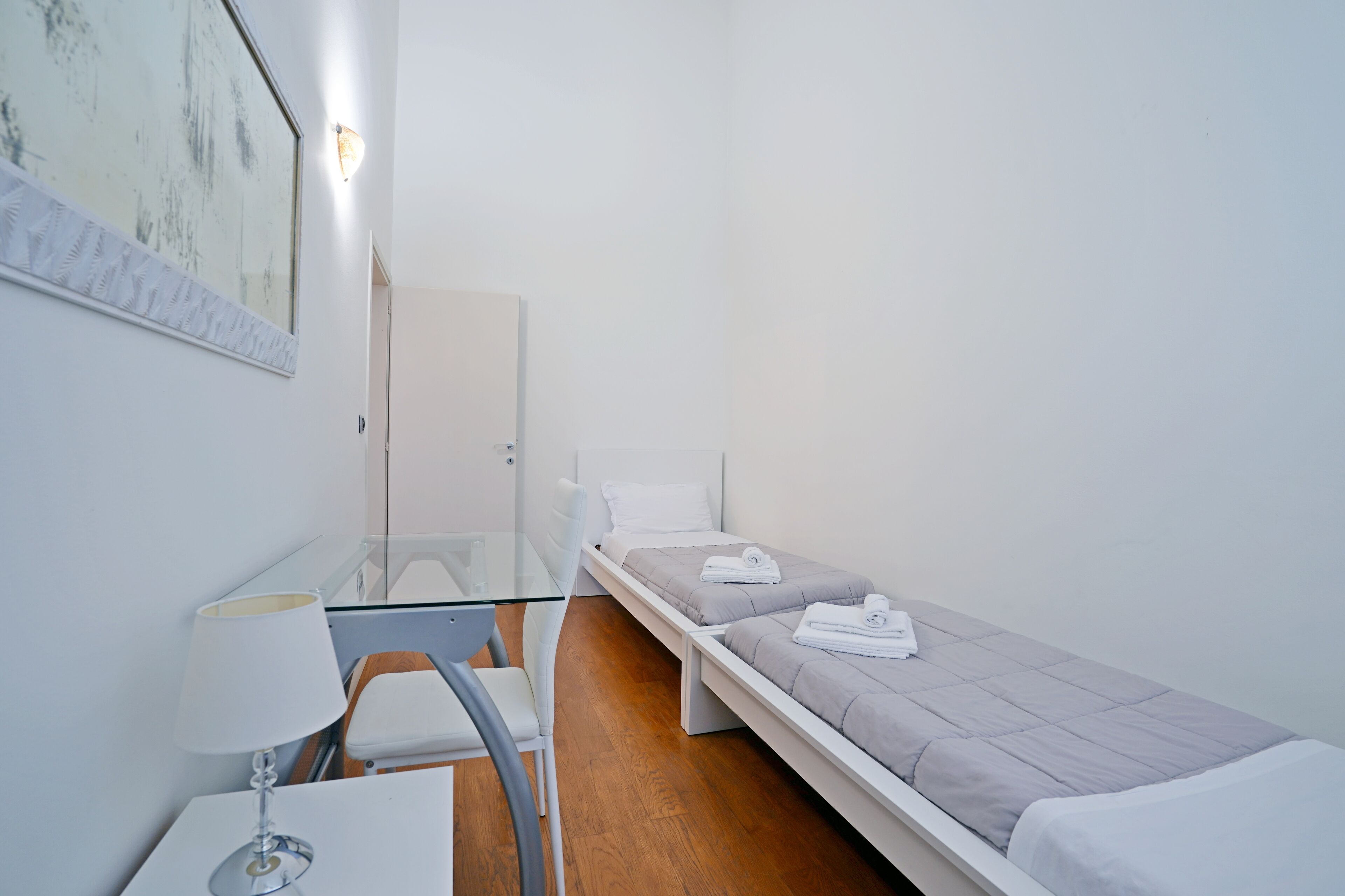 A small, clean room with a single bed, a desk, and a chair.
