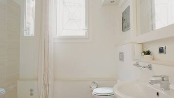 A modern bathroom with a wooden floor, a large window, a bathtub, and a white sink.