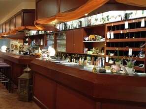 A bar area with wooden shelves, a counter, and various bar tools. - Landhotel Trampe (Breydin)