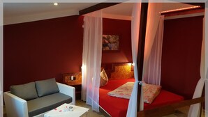 A bedroom with a four-poster bed, a sofa, and a small table. - Landhotel Trampe (Breydin)