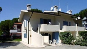 A two-story house with a balcony, satellite dishes, and a small patio area. - Flat in Lignano Riviera (Lignano Sabbiadoro)