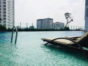 A swimming pool with lounge chairs and a pool ladder. - Andinh Apartment (Ho Chi Minh City)