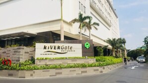 Edifício RiverGate Residence com uma placa, palmeiras e uma estrada pavimentada.