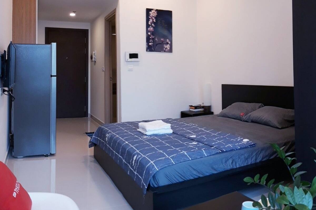Une chambre moderne comprenant un lit, une petite table de chevet, une commode, un climatiseur fixé au mur et une porte donnant sur une autre pièce.