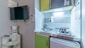Eine kompakte Küchenzeile mit Mikrowelle, Spüle und kleinem Kühlschrank.