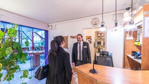 Ein Empfangsbereich mit einem Holztisch, einer Uhr und einem Schild mit der Aufschrift 'Welcome'.