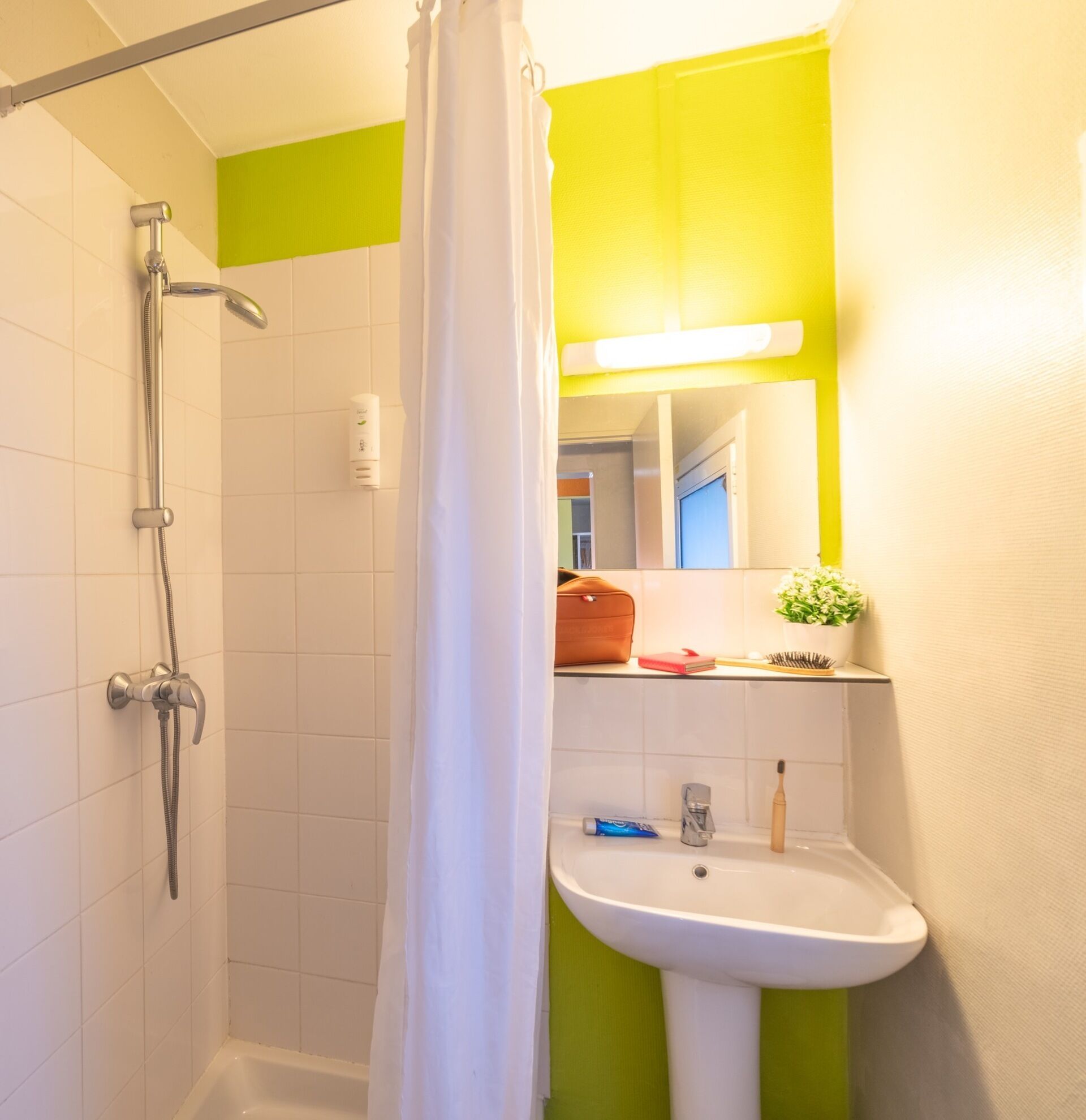 Une salle de bain avec une douche, un lavabo et un miroir.