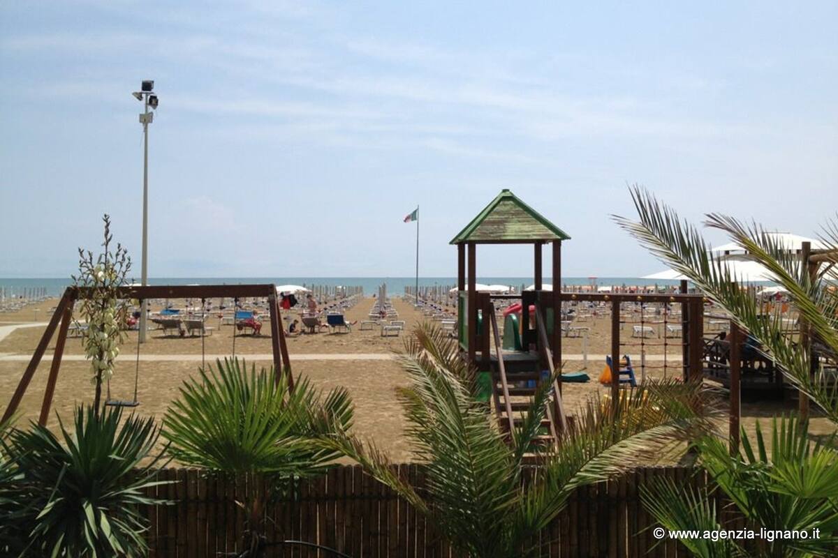 A beach with rows of sun loungers and umbrellas, a lifeguard tower, and a sandy beach area.