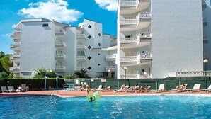 A hotel with a pool area, multiple balconies, and a clear blue sky.