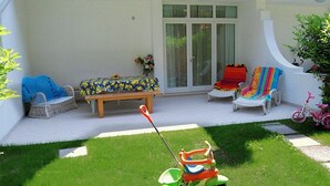 A patio with a lawnmower, a bench, and two chairs. - Villa a Lignano Pineta (Lignano Sabbiadoro)