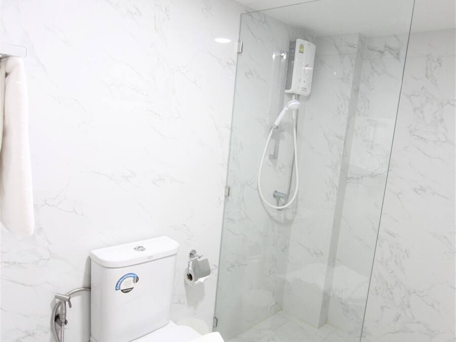 Ein modernes Badezimmer mit Toilette, einer Duschkabine aus Glas und einer Wand mit Marmorplatten.