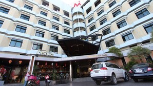 A multi-story hotel with a modern design, featuring balconies on each floor and a prominent entrance with a covered area.