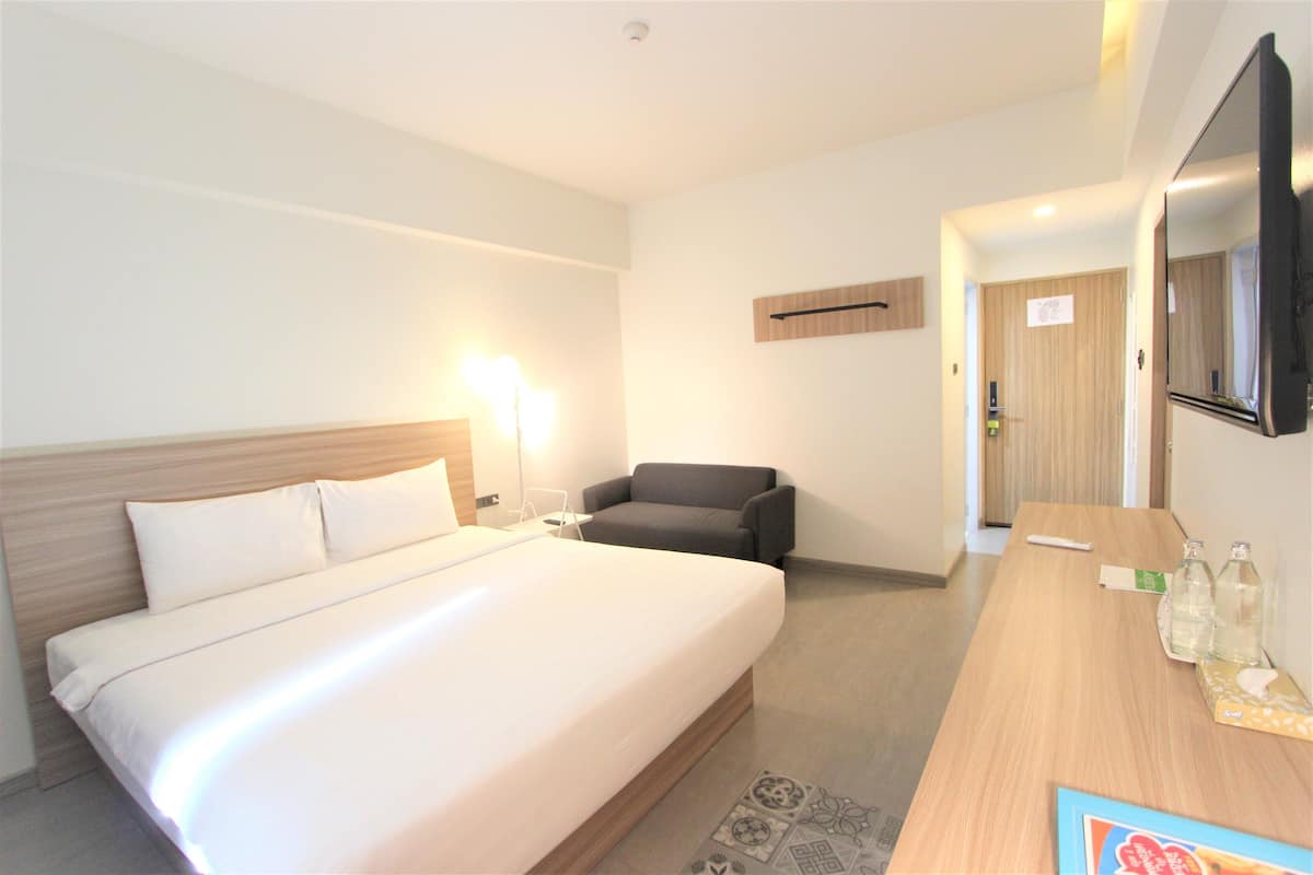 Habitación de hotel con una cama grande, un escritorio con silla, un televisor de pantalla plana y un espejo en la pared.