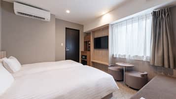 Una habitación de hotel moderna con una cama grande, un televisor, una mesita pequeña y una zona de estar.