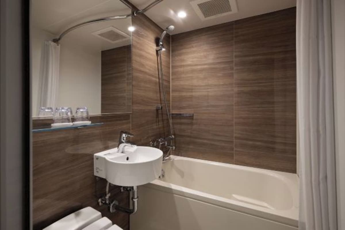 Un baño moderno con una bañera independiente, un lavamanos empotrado y un cabezal de ducha.