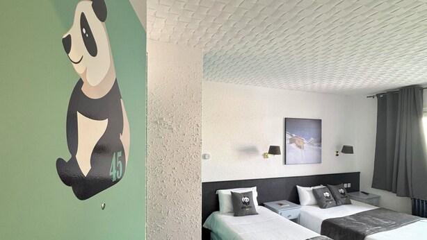 A hotel room with two beds, a green accent wall, a panda decoration, and a textured ceiling. - Hotel Panda (Pas de la Casa)