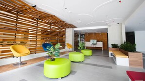A modern lobby with wooden slats, bright green seating, and a reception desk. - Mabolo Garden Flat 1014 (Cebu City)