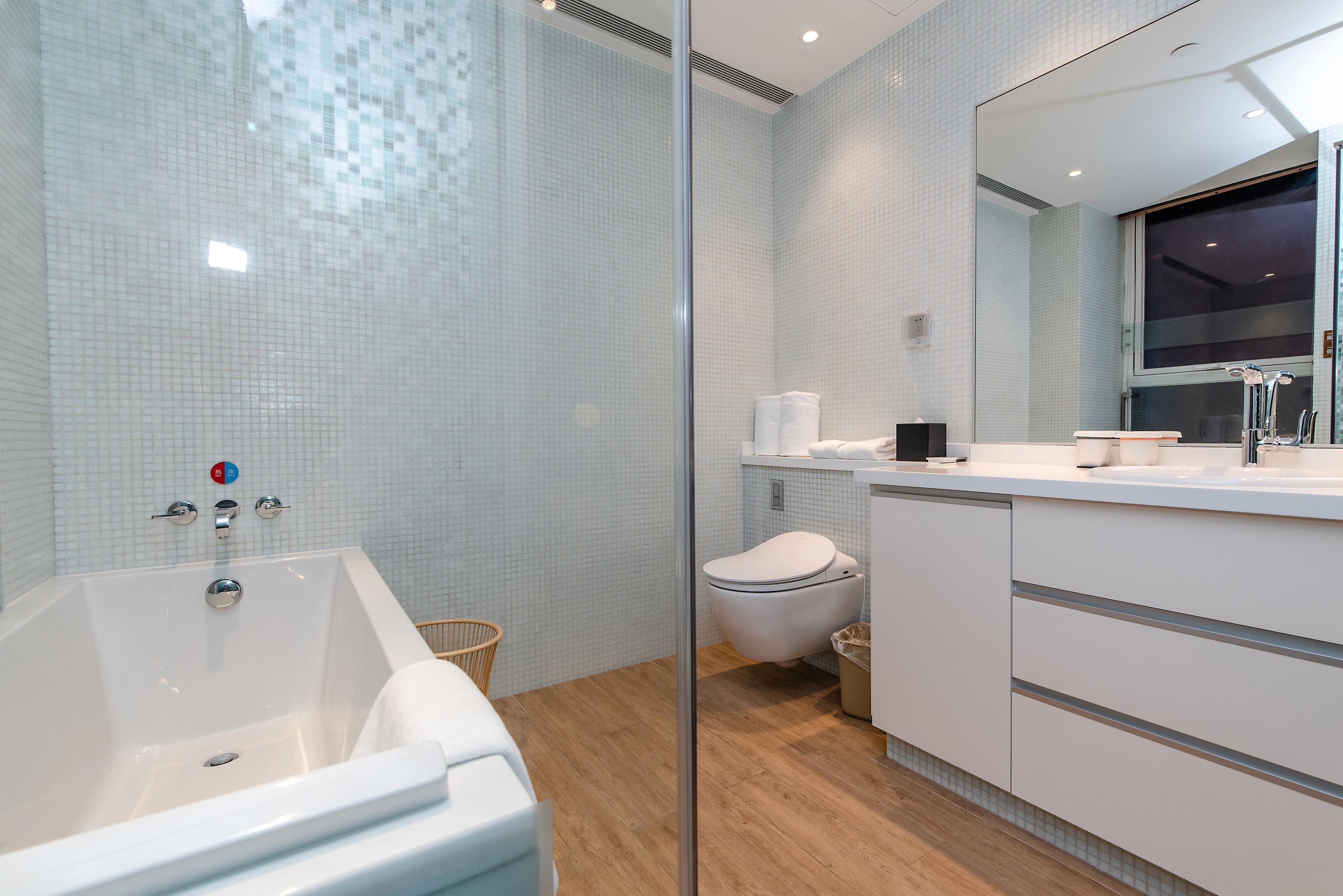 A modern bathroom with a glass shower enclosure, a freestanding bathtub, a toilet, and a vanity with a mirror.