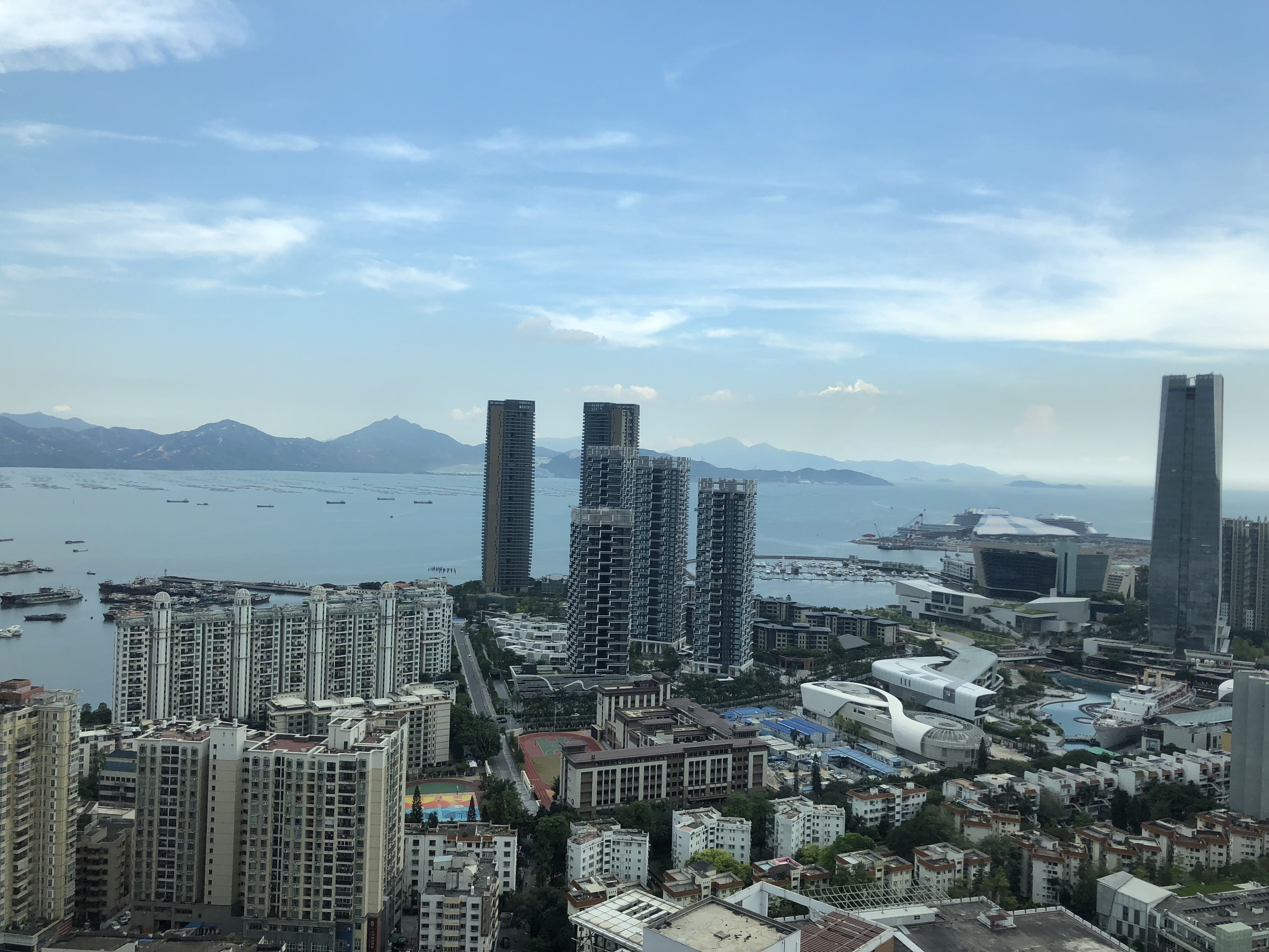 Un quartier urbain dense, avec de nombreux immeubles, un plan d’eau et des montagnes à l’horizon.
