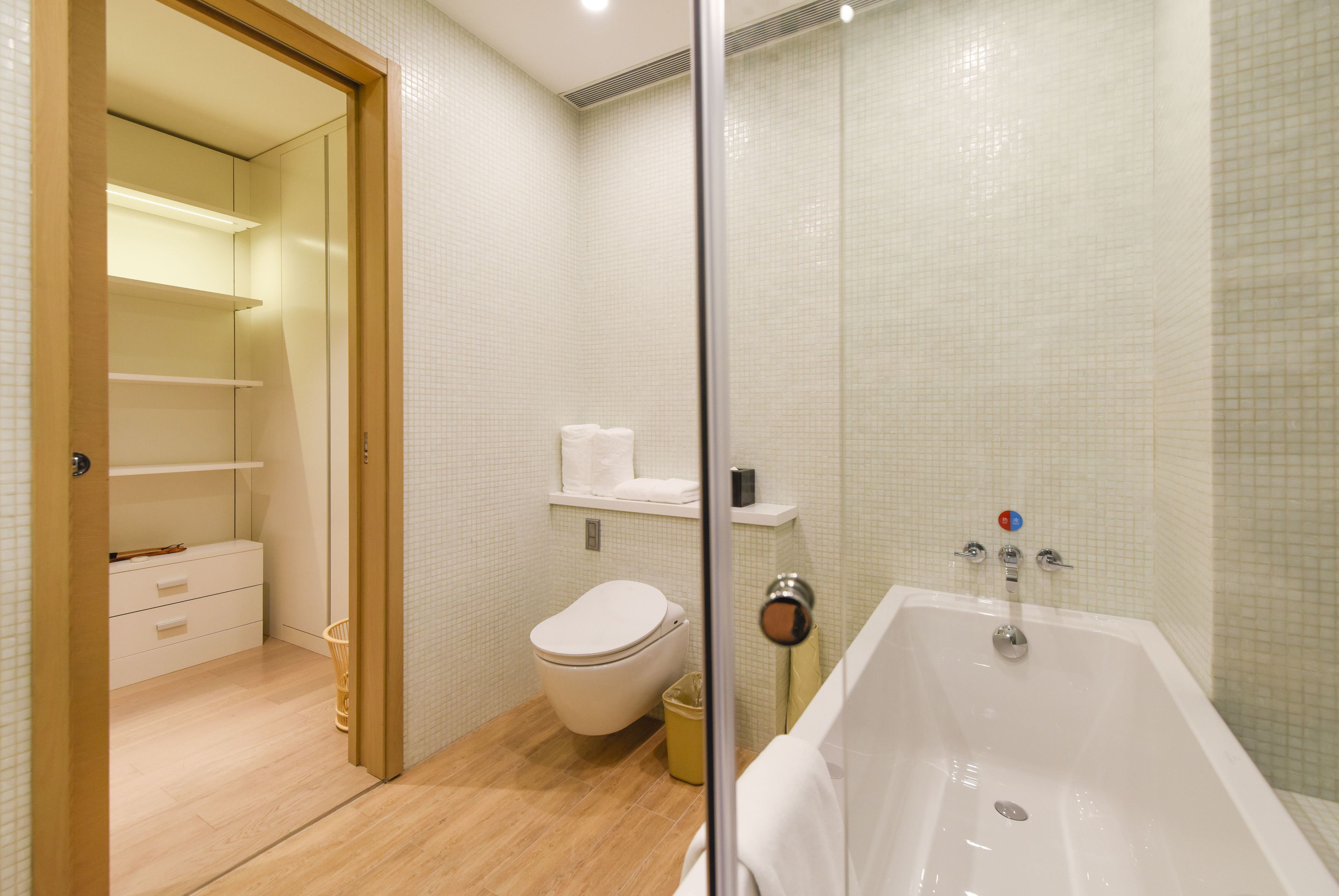 Un baño moderno con bañera, inodoro y zona de ducha con mampara de vidrio.
