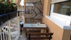 A balcony with a table and chairs, a stone wall, and a window. - St. Peter's Luxury Rooms (Rome)