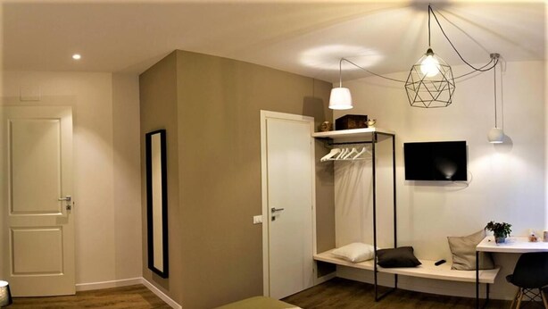 A modern bedroom with a bed, bedside table, and a TV mounted on the wall. - St. Peter's Luxury Rooms (Rome)