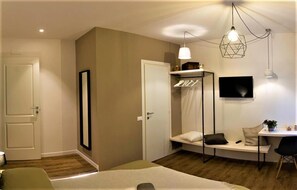 A modern bedroom with a bed, bedside table, and a TV mounted on the wall. - St. Peter's Luxury Rooms (Rome)