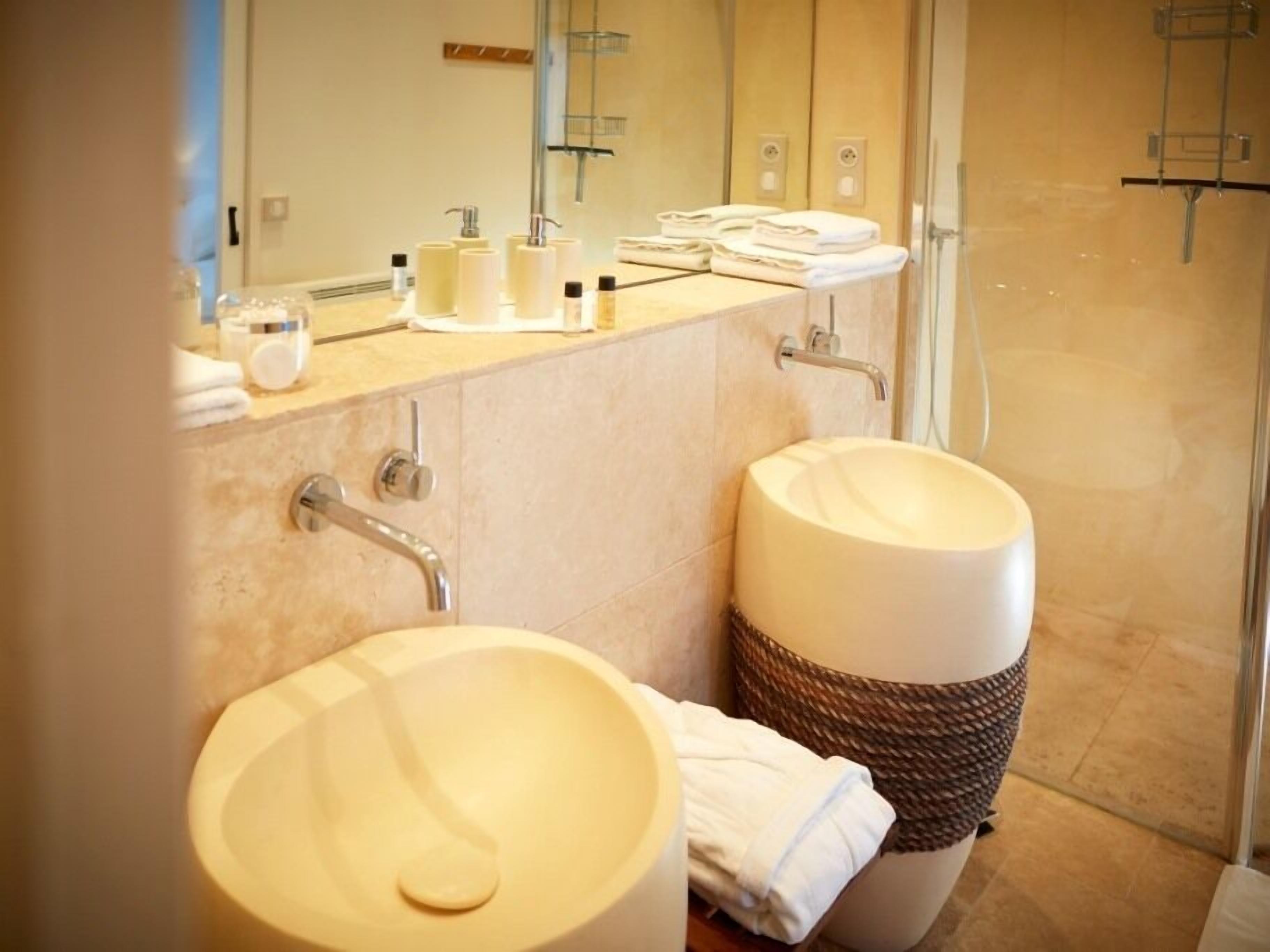 A modern bathroom with two sinks, a large mirror, and a glass shower enclosure.