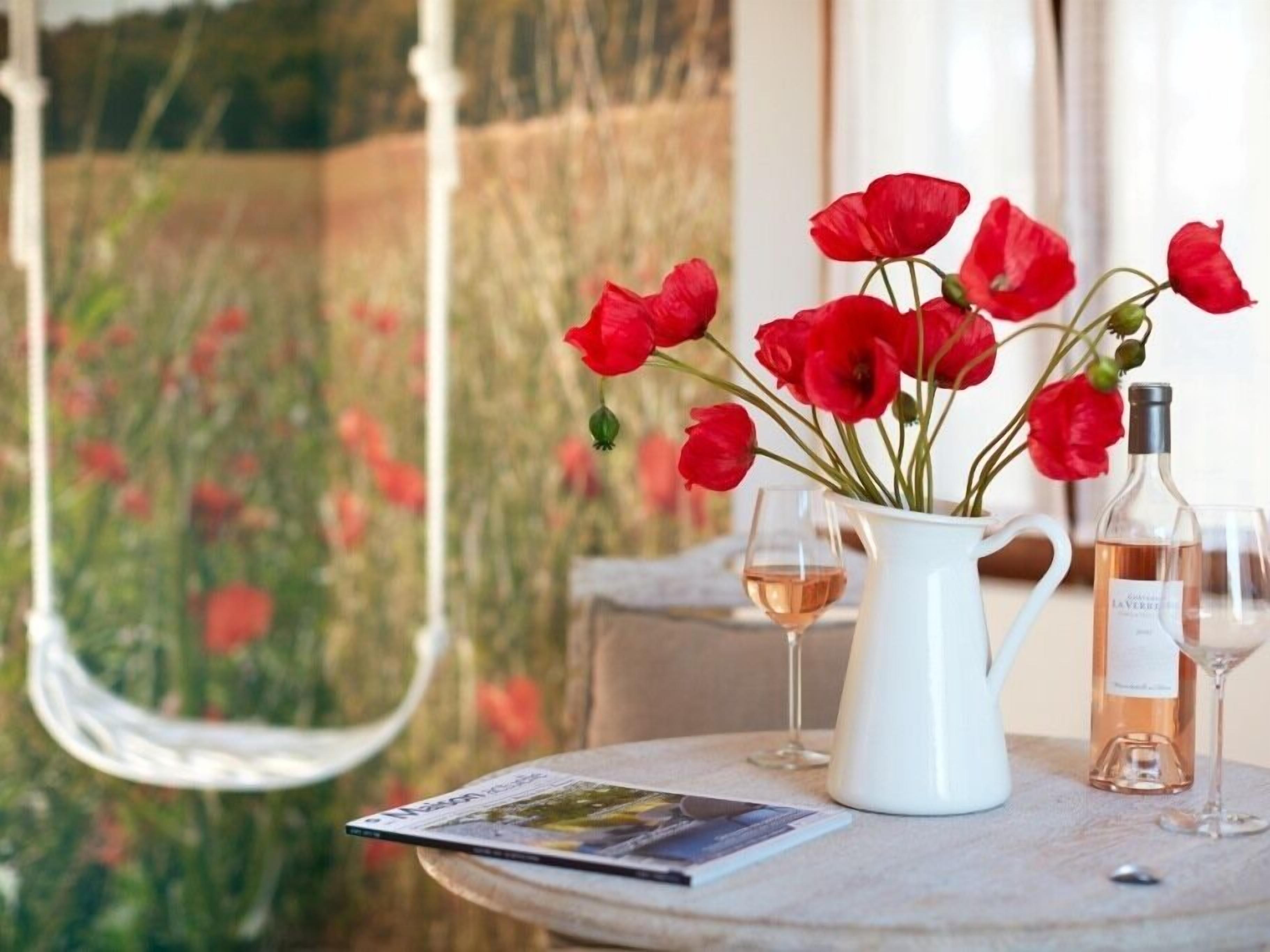 Une table avec un pichet blanc, deux verres à vin et un magazine.